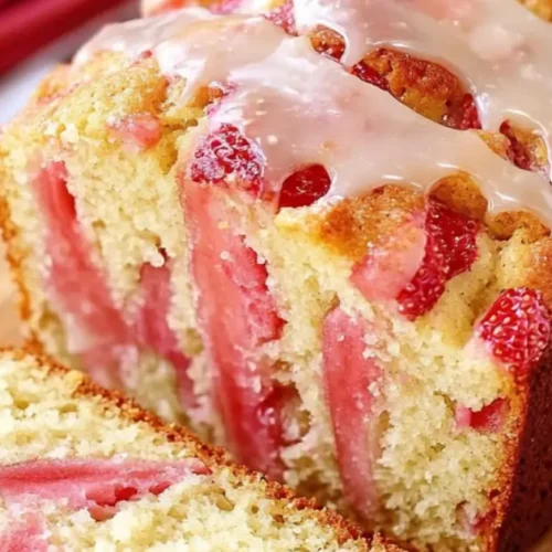 Sliced strawberry rhubarb bread on wooden board with fresh fruit